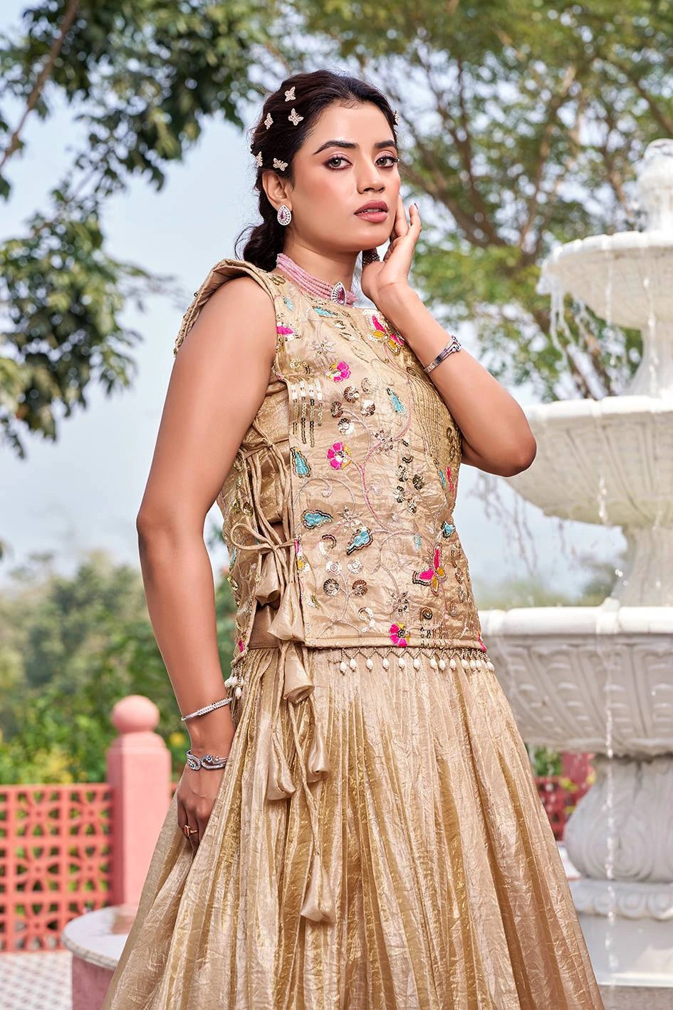 Woman in a traditional embroidered outfit standing outdoors with a fountain in the background